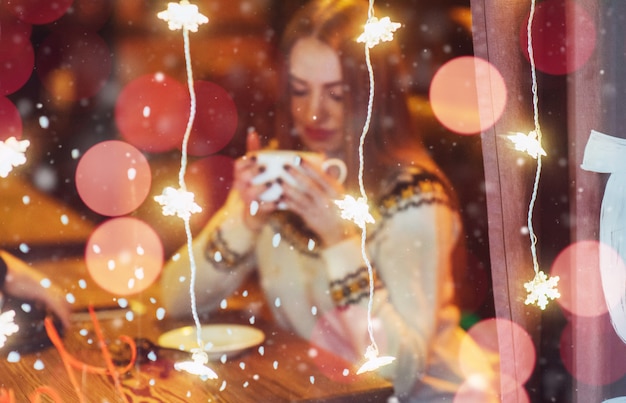 Junge schöne Frau, die im Kaffee, trinkender Kaffee sitzt. Weihnachten, Neujahr, Valentinstag, Winterferien
