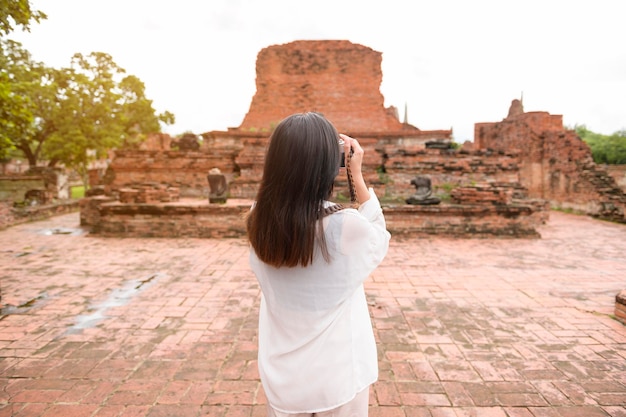 Junge schöne Frau, die im thailändischen historischen Park reist und fotografiert