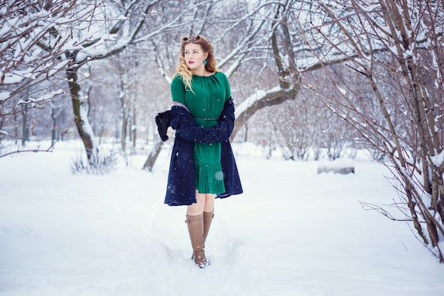 Junge schöne Frau, die in einem Park geht und frische Winterluft atmet und sich wunderbar fühlt. Modell plus Größe