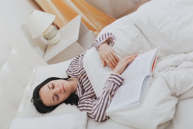 Junge schöne Frau, die mit dem Buch schläft, das sie las