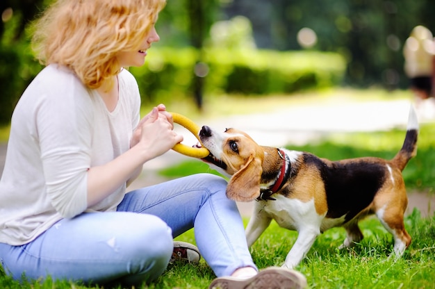 Junge schöne Frau, die mit Spürhundhund im Sommerpark spielt