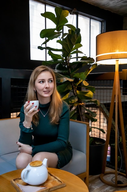 Junge schöne Frau, die mit Tasse Tee im Café sitzt