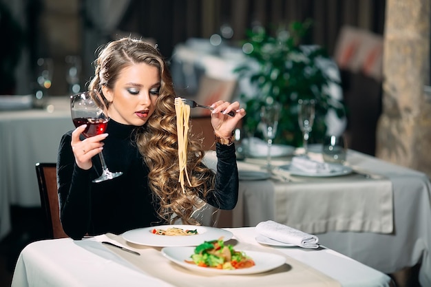 Junge schöne Frau, die Nudeln in einem Restaurant isst.