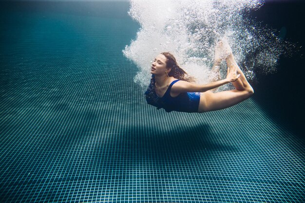 Junge schöne Frau, die unter Wasser schwimmtxA