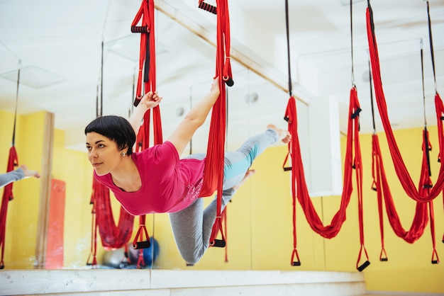 Junge schöne Frau, die Yoga-Fliege mit einer Hängematte praktiziert, das Konzept der geistigen und körperlichen Gesundheit.