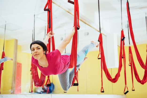 Junge schöne Frau, die Yoga-Fliege mit einer Hängematte praktiziert, das Konzept der geistigen und körperlichen Gesundheit.