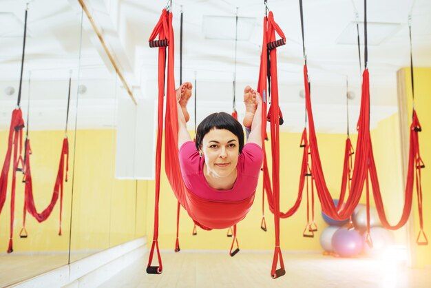 Junge schöne Frau, die Yoga Fly mit einer Hängematte im Studio praktiziert.