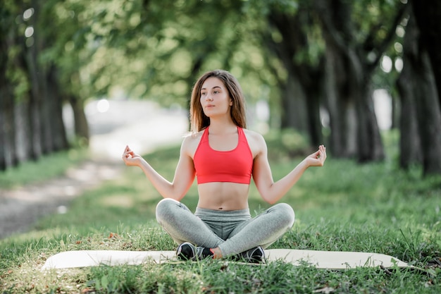 Junge schöne Frau, die Yoga im grünen Park praktiziert