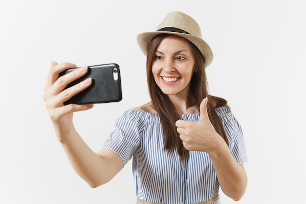 Junge schöne Frau gekleidet blaues Kleid, Hut macht Selfie-Schuss auf Handy oder Videoanruf isoliert auf weißem Hintergrund. Menschen, aufrichtige Emotionen, Lifestyle-Konzept. Werbefläche. Platz kopieren.