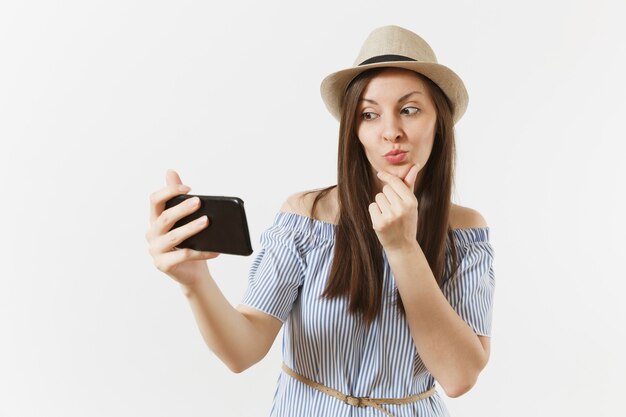 Junge schöne Frau gekleidet blaues Kleid, Hut macht Selfie-Schuss auf Handy oder Videoanruf isoliert auf weißem Hintergrund. Menschen, aufrichtige Emotionen, Lifestyle-Konzept. Werbefläche. Platz kopieren.