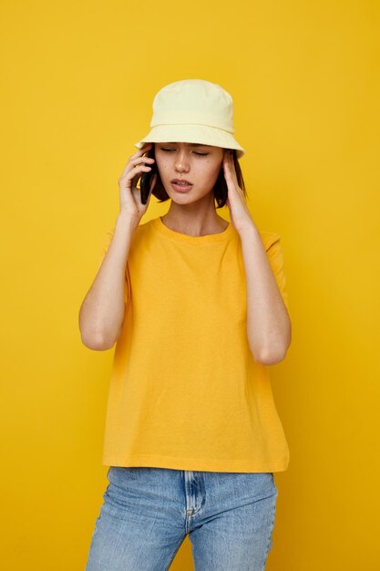 Junge schöne Frau gelbes T-Shirt und Hut im Sommerstil mit unverändertem Telefon-Lifestyle