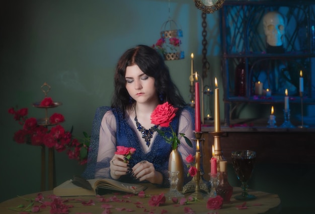 Junge schöne Frau im blauen Vintage-Kleid mit Buch auf dem Tisch im dunklen Raum