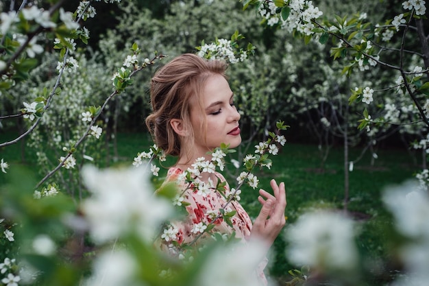 Junge schöne Frau im Garten Cherryblossoming Ein Frauengesicht wird durch weiße Blumen und Kirschzweige versteckt Frühlingsnatur Süßes Aroma Blühender Frühlingskirschbaum Süßer duftender Geruch