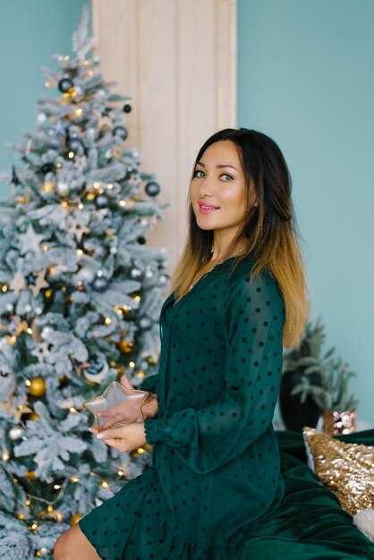 Junge schöne Frau im Kamera-Make-up und Haarstyling mit einem Reifen eines Weihnachtsbaums