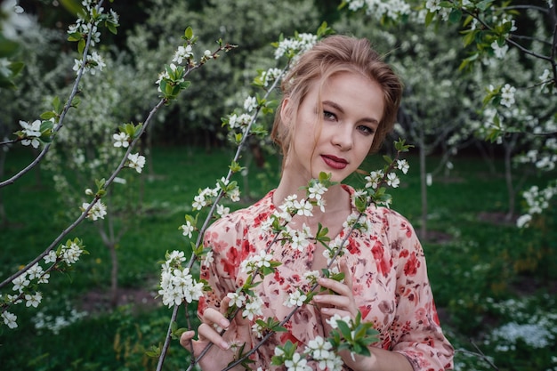 Junge schöne Frau im kirschblühenden Garten.