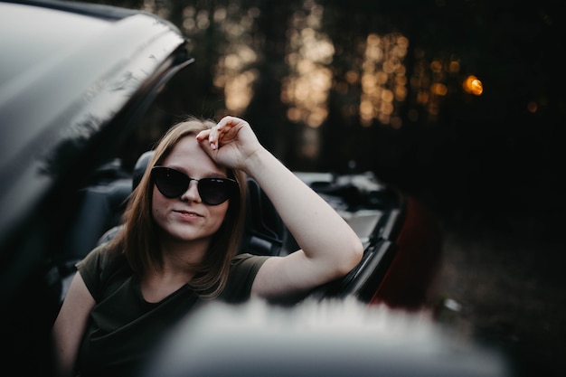 junge schöne Frau im Sommer Cabrio mit Sonnenbrille lächelnd