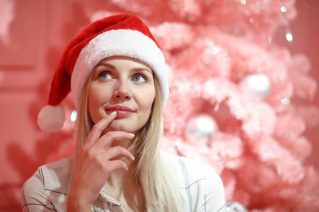 Junge schöne Frau in der roten Weihnachtsmütze, die Weihnachtstag feiert