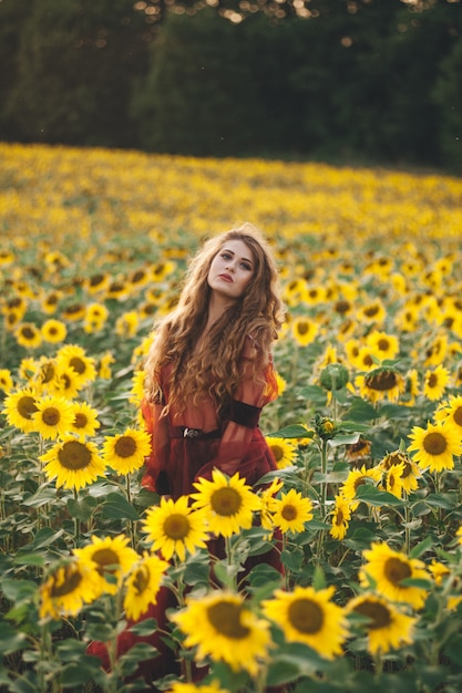 Junge schöne Frau in einem Kleid unter blühenden Sonnenblumen. Agro-Kultur.