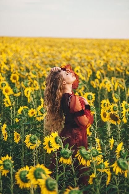 Junge schöne Frau in einem Kleid unter blühenden Sonnenblumen. Agro-Kultur.