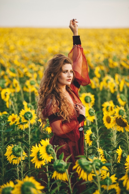 Junge schöne Frau in einem Kleid unter blühenden Sonnenblumen. Agro-Kultur.