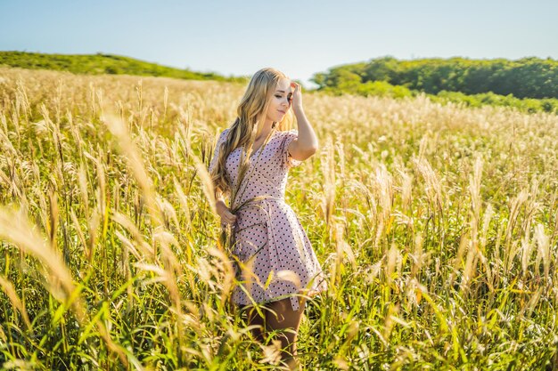 Junge schöne Frau in Herbstlandschaft mit trockenen Blumen Weizenspitzen Mode Herbst Winter Sonniges Herbstmodefoto