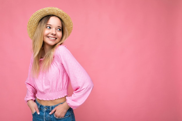 Junge schöne Frau in stylischer rosa Sommerbluse und trendigen Strohhut positive weibliche Shows