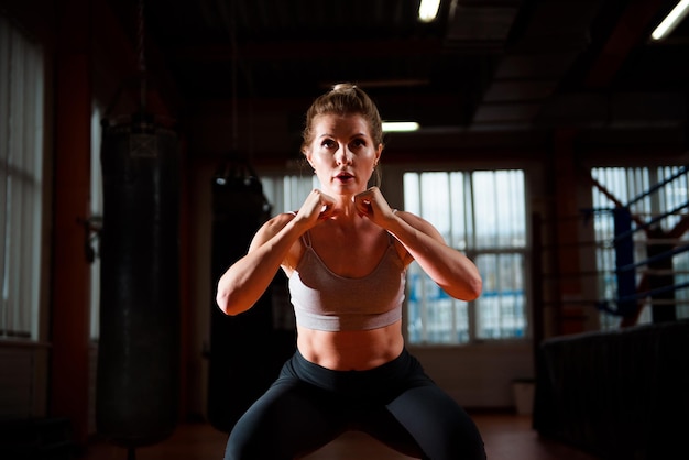 Junge schöne Frau macht Übungen im Fitnessstudio Glückliches lächelndes Mädchen, das ihren Trainingsprozess genießt