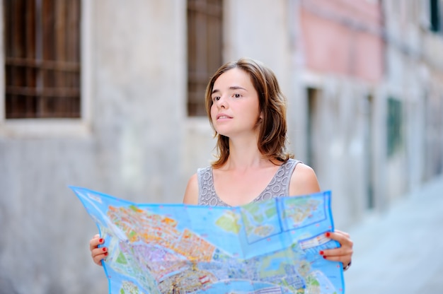 Junge schöne Frau mit der Papierkarte, die auf Straße in Venedig, Italien steht