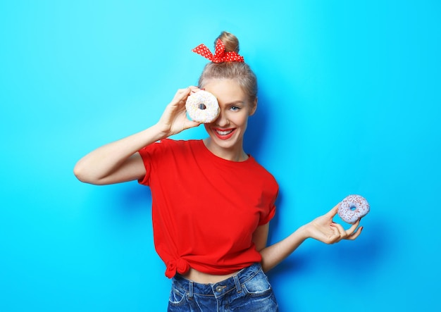 Junge schöne Frau mit Donuts auf blauem Hintergrund