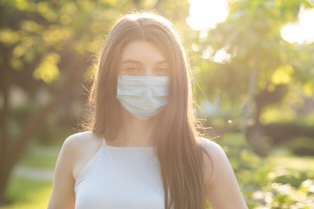 Junge schöne Frau mit einer Gesichtsmaske im Park