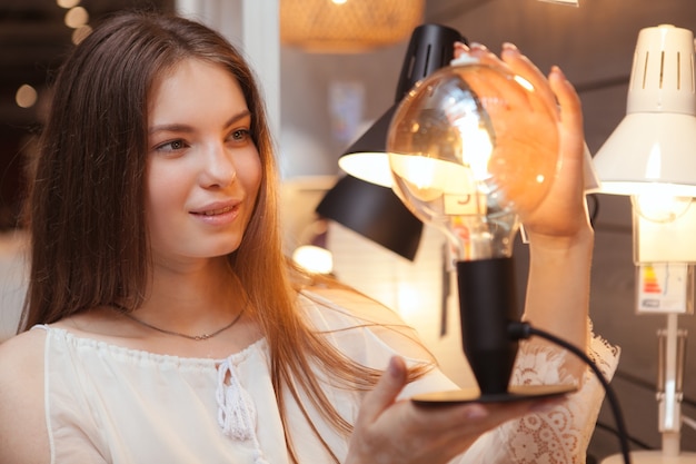 Junge schöne Frau mit einer Lampe in einem Geschäft