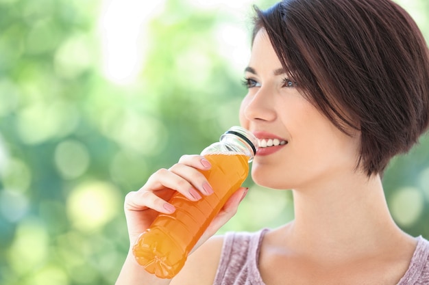 Junge schöne Frau mit Flasche Orangensaft im Freien