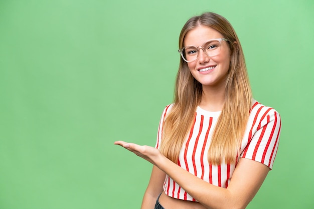 Junge schöne Frau mit isoliertem Hintergrund präsentiert eine Idee und blickt lächelnd in die Richtung