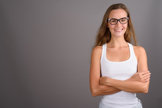 Junge schöne Frau mit langen blonden Haaren gegen grauen Hintergrund