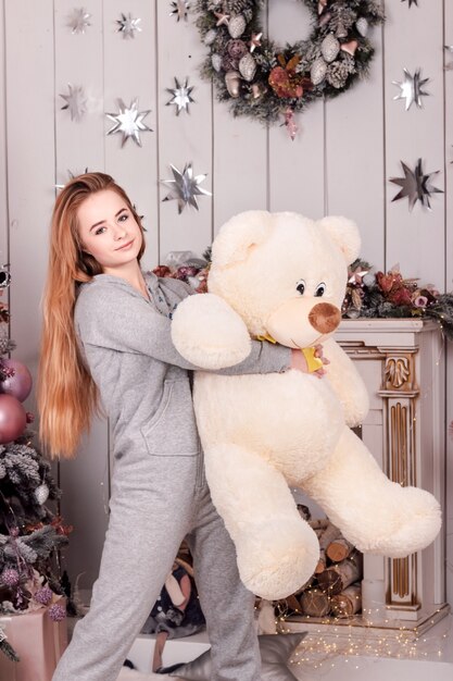 Junge schöne Frau mit langen, fließenden Haaren, die einen großen Teddybären hält