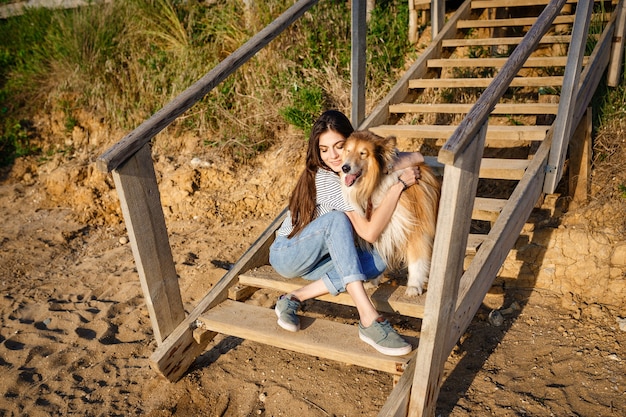 Junge schöne Frau mit langen Haaren, die mit Colliehund gehen. Draußen im Park. in der Nähe des Meeres, Sommer Beatch