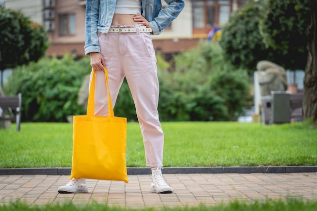 Junge schöne Frau mit Leinen-Öko-Tasche auf Stadthintergrund