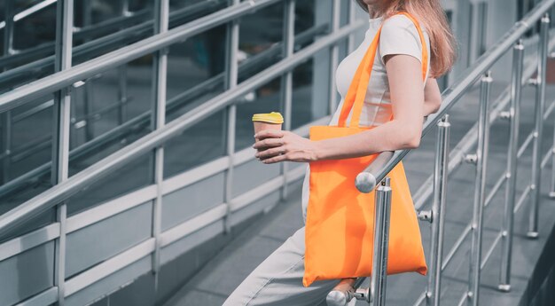 Junge schöne Frau mit Leinen-Öko-Tasche auf Stadthintergrund