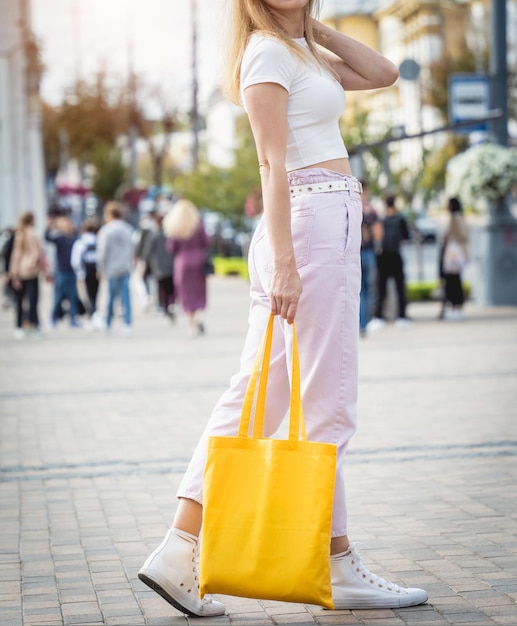 Junge schöne frau mit leinen-öko-tasche auf stadthintergrund