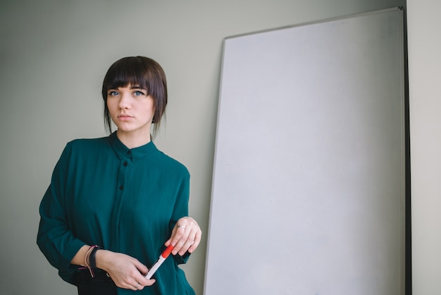 Junge schöne Frau mit Markierungsschreiben oder -zeichnung steht am Whiteboard. Unternehmenskonzept