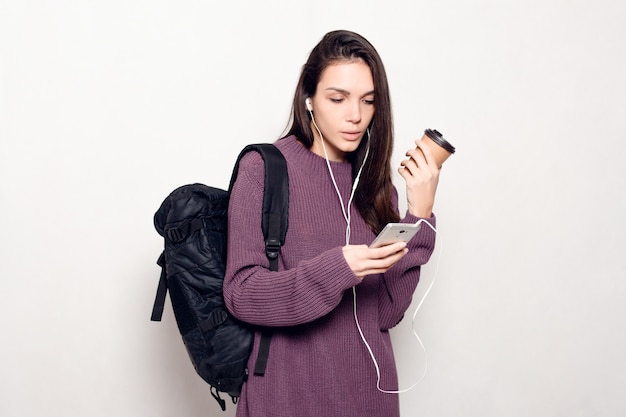 Foto junge schöne frau mit smartphone und rucksack