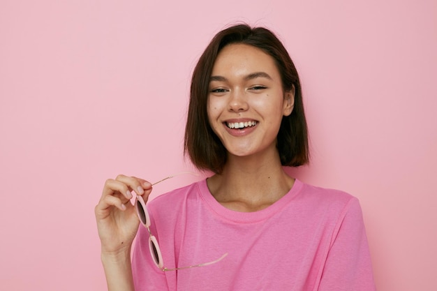 Junge schöne Frau mit Sonnenbrille ein rosa T-Shirt isoliert Hintergrund