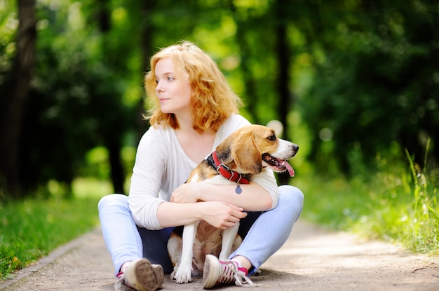 Junge schöne Frau mit Spürhundhund im Sommerpark