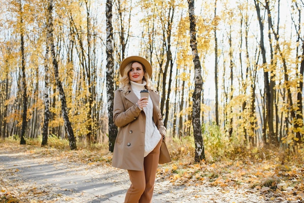Junge schöne Frau mit Tasse Kaffee im Herbstpark