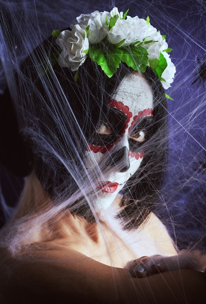 Foto junge schöne frau mit traditioneller mexikanischer totenmaske. calavera catrina. zuckerschädel make-up. frau, gekleidet in einen rosenkranz