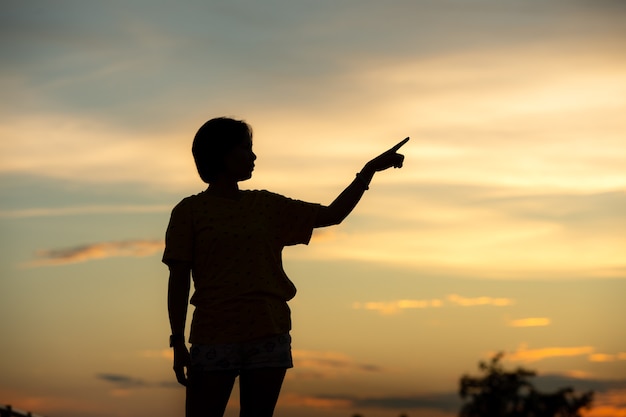 Junge schöne Frau schaut bei Sonnenuntergang hoffnungsvoll auf ihre Hände. Konzepterfolg in der Hand