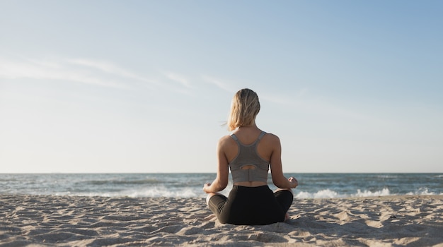 Junge schöne Frau sitzt am Strand