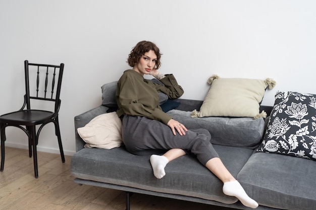 Foto junge schöne frau sitzt in einem hemd auf dem sofa im studio