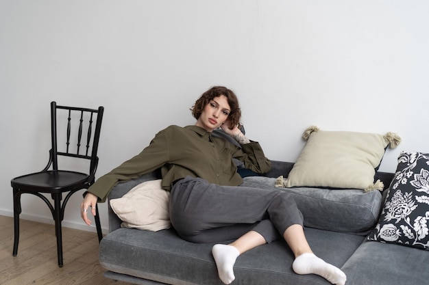 Foto junge schöne frau sitzt in einem hemd auf dem sofa im studio