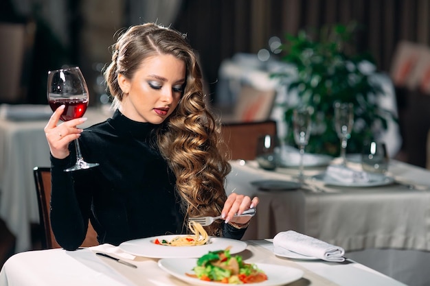 Junge schöne Frau trinkt Wein in einem Restaurant.
